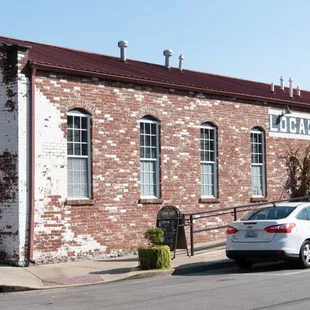 a white car parked in front of a brick building