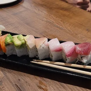 a sushi platt with chopsticks and a glass of water