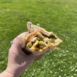 a person holding a burrito in their hand