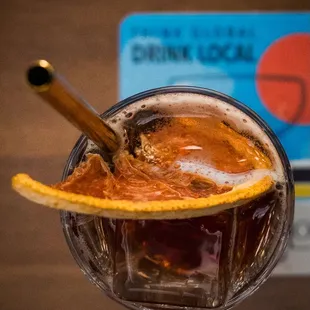 a drink in a glass with an orange peel