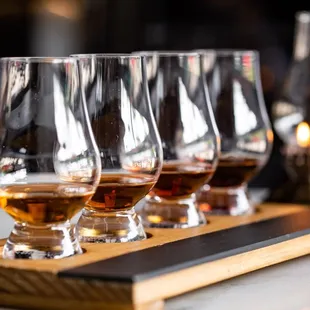 four glasses of whisky on a wooden tray