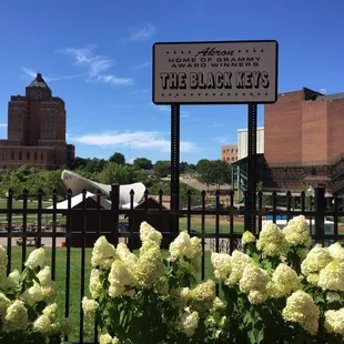 a black and white sign with white flowers in the foreground