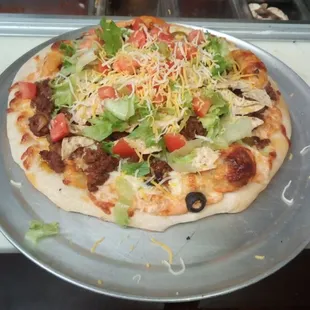 a pizza with lettuce, tomatoes, cheese, and other toppings