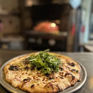 a pizza with greens on top