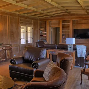 Media area includes large screen tv and comfortable seating on leather couch and chairs.