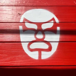a painted mask on a red wall