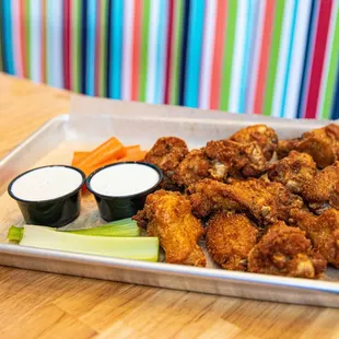 a tray of fried chicken with dips and celery