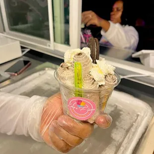 a hand holding a cup of ice cream