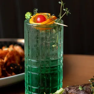 a green glass with a garnish on top