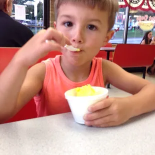 a young boy eating a bowl of ice cream