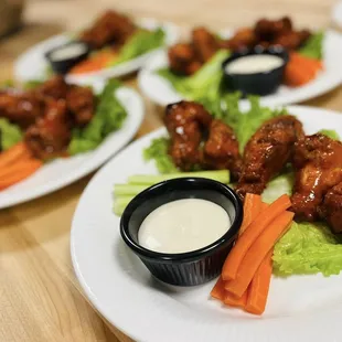 a plate of buffalo wings and carrots