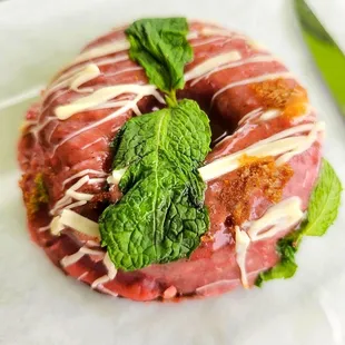 a donut with white icing and mint leaves