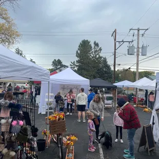 a crowd of people shopping at a farmers market