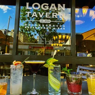 four cocktails on a table in front of a window