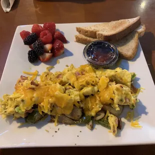 Daily breakfast scramble with ham, broccoli, and cheddar with fresh fruit and toast.
