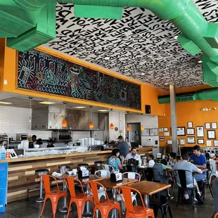 the inside of a restaurant with tables and orange chairs