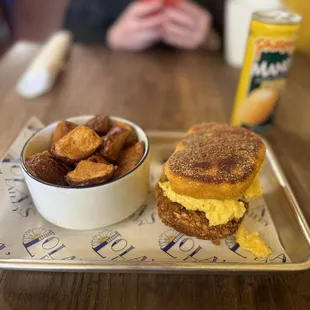 a breakfast sandwich and a bowl of fried potatoes