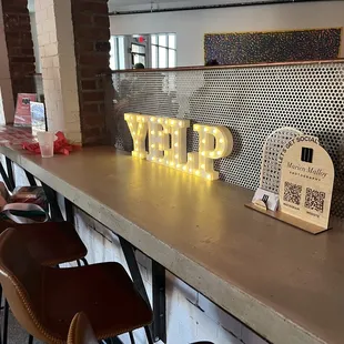 a row of bar stools and a neon sign
