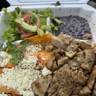 Enchiladas with chicken. Black beans and rice is under the chicken.