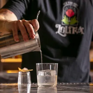 a bartender pouring a drink into a glass
