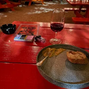 a plate of food and a glass of wine on a picnic table