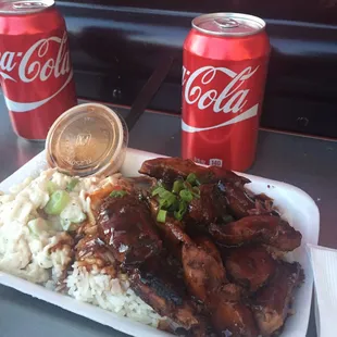 a plate of ribs and rice with a coke