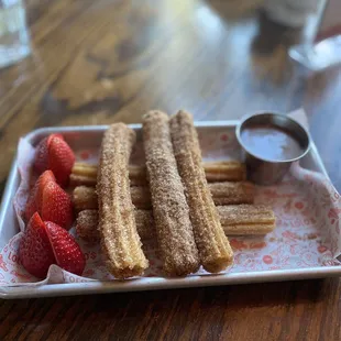 a plate of churros and strawberries