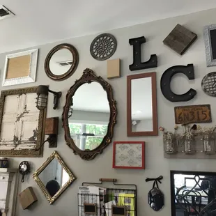 a wall full of frames and mirrors