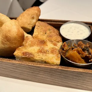 a wooden tray with bread and dips