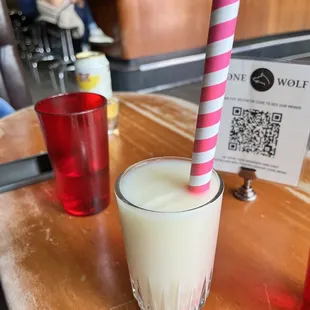 a glass of milk with a pink and white striped straw