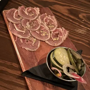 a platter of sliced meat and pickles