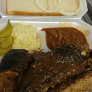 a tray of ribs, beans, and bread
