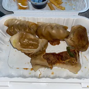 dumplings and fries in a styrofoam container