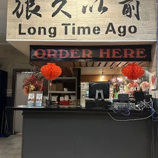 a restaurant counter with a sign above it