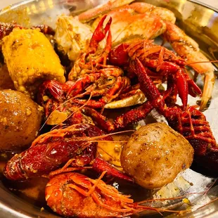 a bowl of lobsters, potatoes, and corn