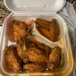 chicken wings and carrots in a styrofoam container