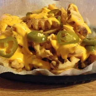 a plate of fries with cheese and jalapenos
