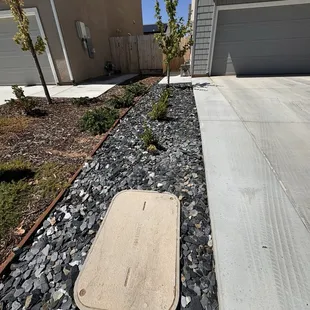 slate chip rocks along with 3 new bushes and waterline leading to backyard