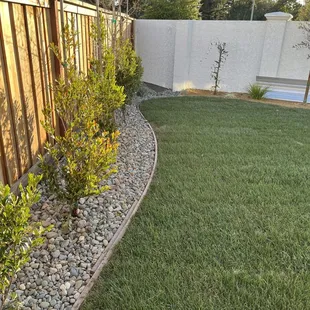 a fenced backyard with a pool in the background
