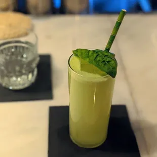 a drink with a straw and a green leaf garnish