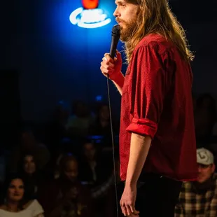 a man in a red shirt holding a microphone