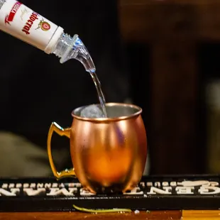 pouring water into a copper mug
