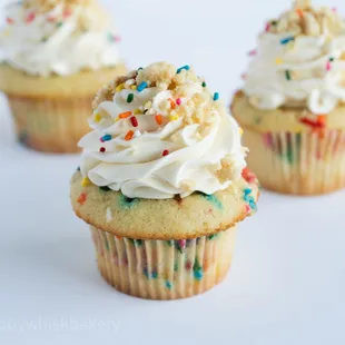 three cupcakes with white frosting and sprinkles