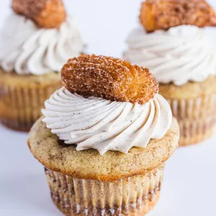 three cupcakes with cream frosting and cinnamon sprinkles