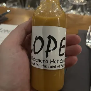 a person holding a bottle of hot sauce