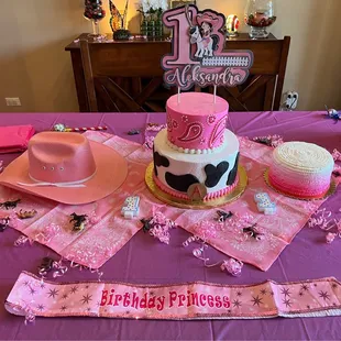 a table with a pink table cloth and a cow themed cake