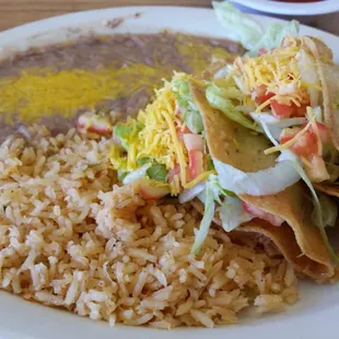 Two tacos with rice and beans.