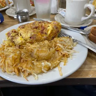 Meat lovers omelet...partially eaten...with toast and shredded hash browns.