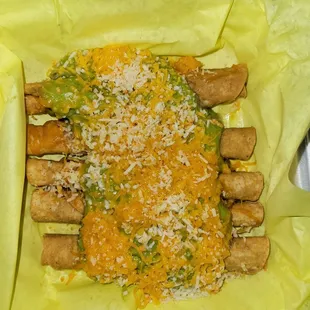 5 rolled tacos with cheese and guacamole.