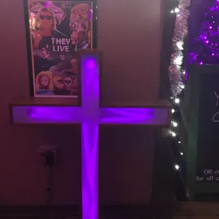 a purple lighted cross in front of a movie poster